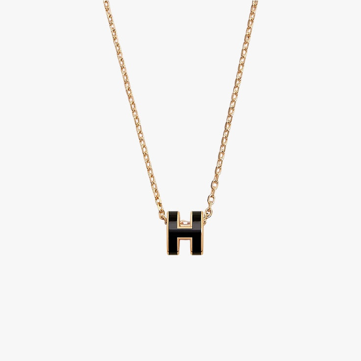 Necklace with a black 'H' pendant on a gold chain against a white background
